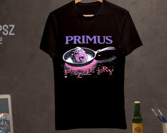 May include: Black cotton t-shirt with a purple and pink graphic of a creature in a frying pan. The text "PRIMUS" and "FRIZZLE FRY" are printed on the shirt.