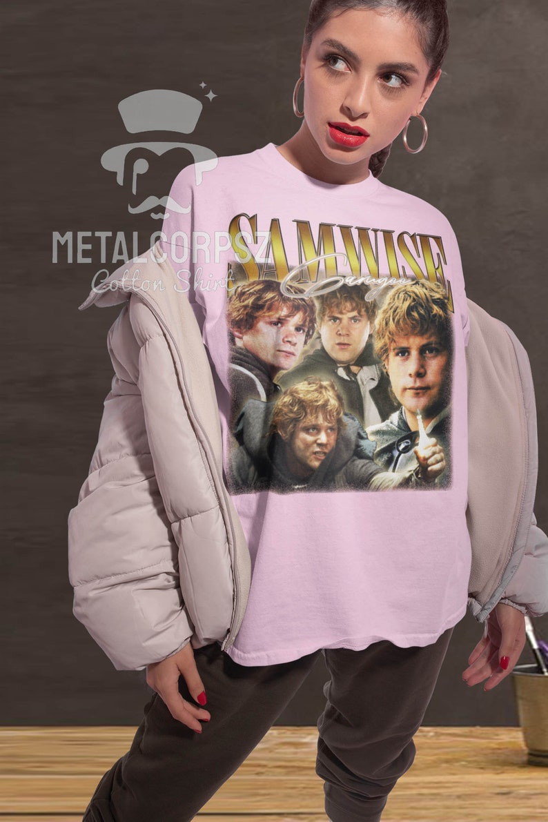 May include: A pink t-shirt with a vintage-style graphic of Samwise Gamgee from the Lord of the Rings movies. The graphic features four images of Samwise Gamgee in different poses. The text "Samwise Gamgee" is printed in gold letters above the graphic.