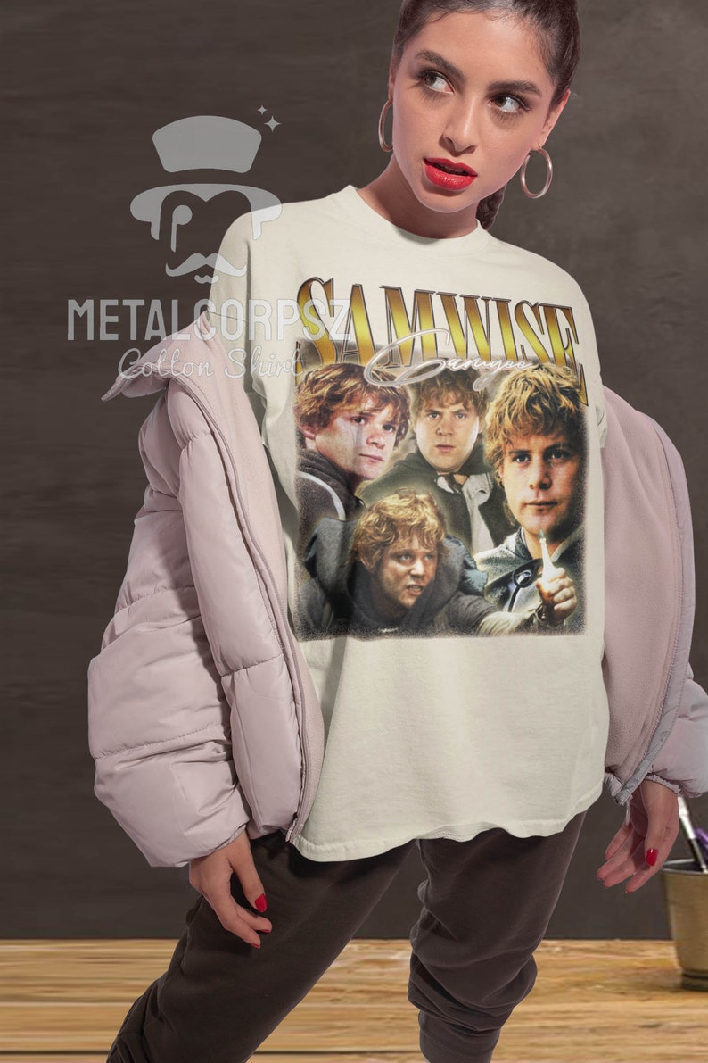 May include: A white t-shirt with a vintage-style graphic of Samwise Gamgee from the Lord of the Rings. The graphic features four images of Samwise Gamgee in different poses. The text "SAMWISE Gamgee" is printed in gold letters above the graphic.