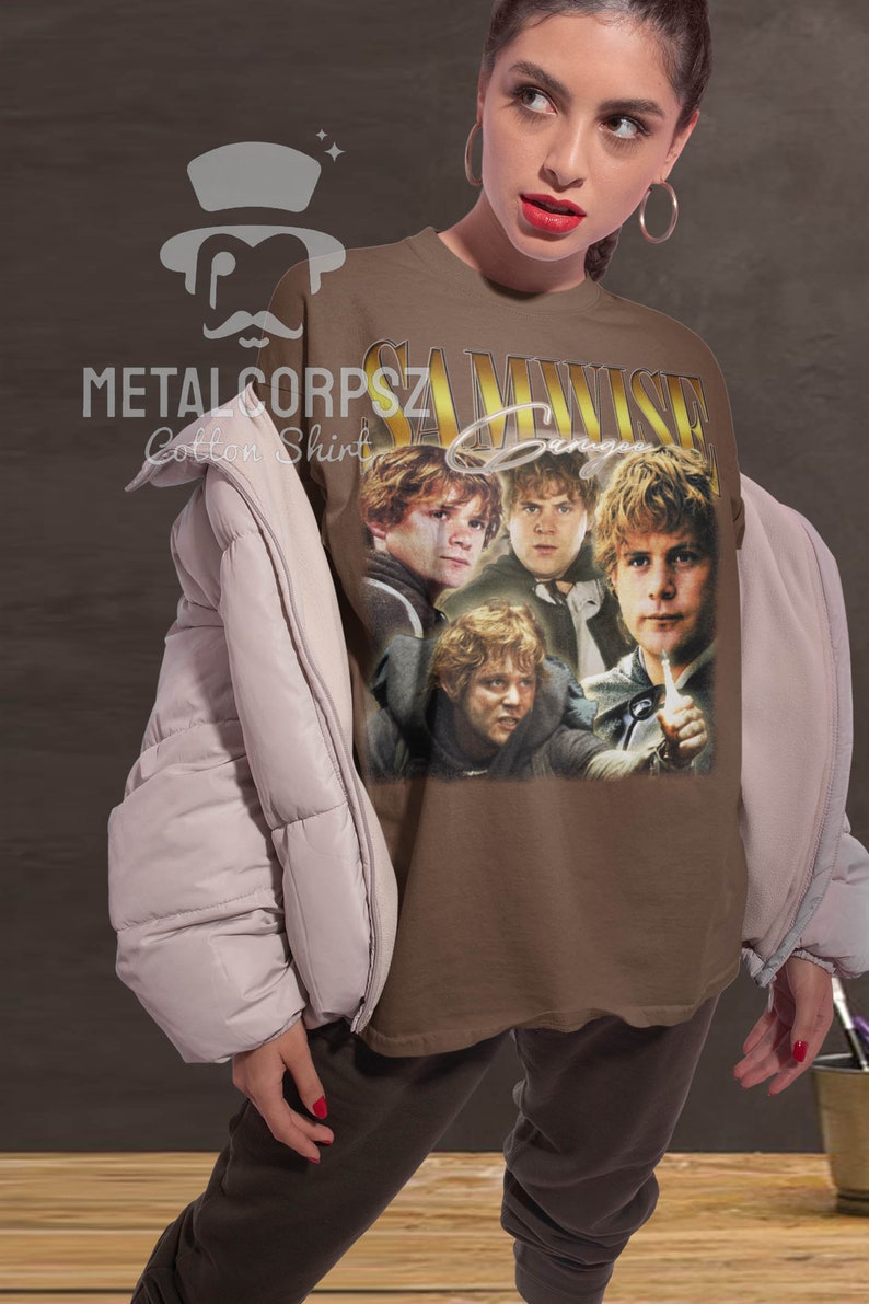May include: A brown t-shirt with a vintage-style graphic of Samwise Gamgee from the Lord of the Rings. The graphic features four images of Samwise Gamgee in different poses. The text "Samwise Gamgee" is printed in gold letters above the graphic.