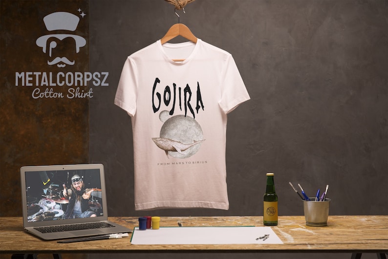 May include: White cotton t-shirt with a black graphic print of the band Gojira. The graphic features a whale swimming around a planet with the text "From Mars to Sirius".