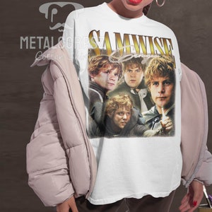 May include: White t-shirt with a vintage-style graphic of Samwise Gamgee from the Lord of the Rings. The graphic features four images of Samwise Gamgee in different poses. The text "SAMWISE Gamgee" is written in gold letters above the images.