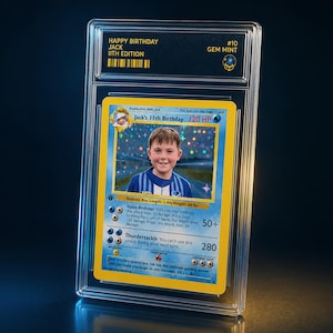 Op de afbeelding: Een aangepaste Pokémon-kaart in een beschermhoes. De kaart toont een foto van een jongen en leest "Happy Birthday Jack, 11th Edition". De kaart is beoordeeld als "GEM MINT" en heeft de tekst "Jack's 11th Birthday 120 HP" en "Thundertackle."