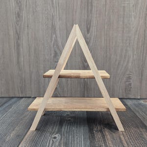 May include: A wooden two-tiered stand shaped like a triangle. The stand is made of natural wood and has a rustic look.