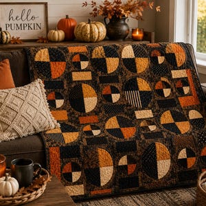 May include: A quilt featuring a geometric pattern of circles and rectangles in shades of black, orange, and cream. The fabric displays various textures including polka dots and stripes, with visible machine quilting stitches throughout the surface.