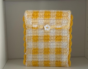 May include: A rectangular crochet pouch featuring a yellow and white checkered pattern. The pouch has a flap closure secured with a white flower-shaped button. The edges of the pouch are finished with a decorative yellow scalloped crochet border.