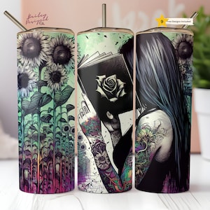 May include: Three stainless steel tumblers with different designs. The first tumbler features a field of sunflowers in shades of green, purple, and pink. The second tumbler features a woman with tattoos holding a book with a rose on the cover. The third tumbler features a woman with tattoos and long black hair.