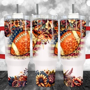 May include: Three white insulated tumblers with a football and floral design. The design includes an American flag, a football with a leopard print pattern, and colorful flowers. Each tumbler has a red handle and a silver straw.