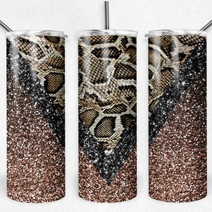 Pu&ograve; includere: Tre bicchieri in acciaio inossidabile con coperchi e cannucce. Il design presenta un motivo a pelle di serpente marrone e beige, contrastato da un gradiente di glitter neri e marroni. I bicchieri sono progettati per bevande fredde.