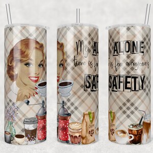 May include: A stainless steel tumbler with a plaid pattern and a retro-style illustration of a woman drinking coffee. The tumbler has the text "My alone time is for everyone's safety" printed on it.