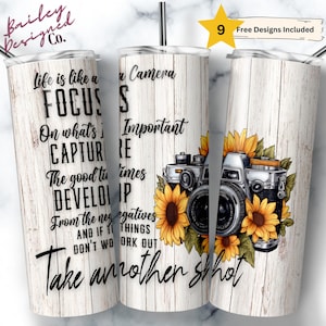 Puede incluir: Un vaso de acero inoxidable blanco con un patrón de veta de madera y una cita sobre la vida que es como una cámara. La cita dice: "La vida es como una cámara, enfócate en lo importante, captura los buenos momentos, desarrolla a partir de los negativos, y si las cosas no funcionan, toma otra foto." El vaso está decorado con una cámara vintage y girasoles.