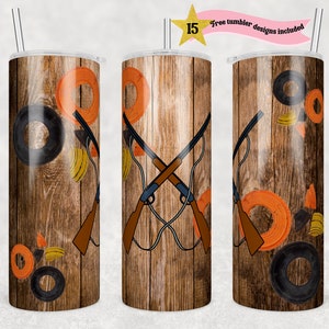 Op de afbeelding: Een roestvrijstalen tumbler met een houtnerfdesign met gekruiste jachtgeweren, kleiduifjes en een doelwit. De tumbler is 20 ounce en heeft een dubbelwandig geïsoleerd ontwerp.