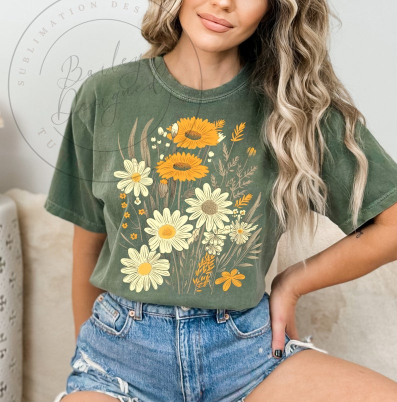 May include: A green t-shirt with a floral print featuring yellow and white flowers. The flowers are arranged in a bouquet-like design.