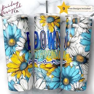 May include: A white stainless steel tumbler with a floral design featuring blue and yellow flowers. The tumbler has the text "Down Syndrome Mom" in blue and yellow lettering.