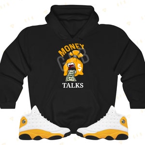 May include: Black hoodie with a graphic of a money bag with a dollar sign and the text "Money Talks". A pair of white and yellow sneakers are also pictured.