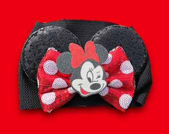 May include: Black headband with a red and white polka dot bow and a Minnie Mouse character in the center.