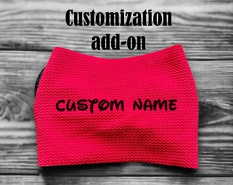 May include: Red fabric headband with the text "CUSTOM NAME" in black lettering. The headband is a customization add-on.