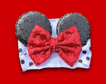 May include: A white headband with black polka dots and a red sequined bow. The headband has two black sequined ears on top.