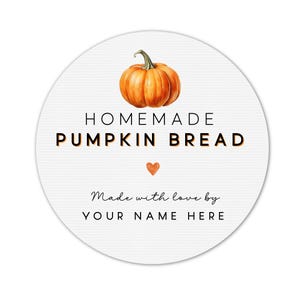 May include: A round white label with the words "HOMEMADE PUMPKIN BREAD" in black and orange. A watercolor illustration of an orange pumpkin sits above the text. Below the text is a small orange heart and the words "Made with love by YOUR NAME HERE."