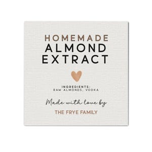 May include: Square label with the text "HOMEMADE ALMOND EXTRACT" in brown and black. Below the text is a heart graphic. The ingredients are listed as raw almonds and vodka. The text "Made with love by THE FRYE FAMILY" is also included.