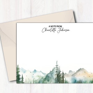 May include: A note card with a watercolor illustration of a mountain range with trees and a light blue sky. The text "A Note From Charlotte Johnson" is at the top of the card.