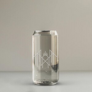 A clear glass can with water inside, featuring a logo or design on the side.