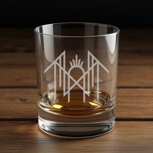 A clear glass with a white logo on it, placed on a wooden surface.