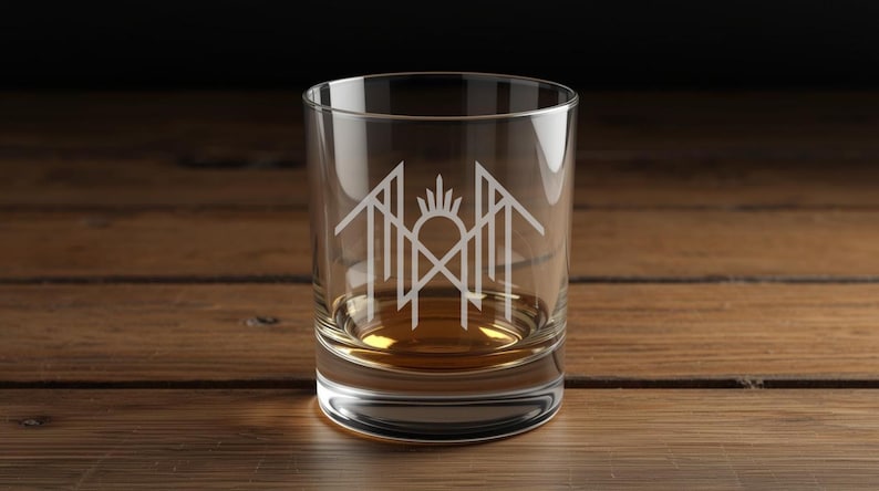 A clear glass with a white logo on it, placed on a wooden surface.