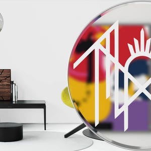 a modern and stylish living room with a large round mirror, a black coffee table, and various decorative items such as a clock, a vase, and a sculpture.