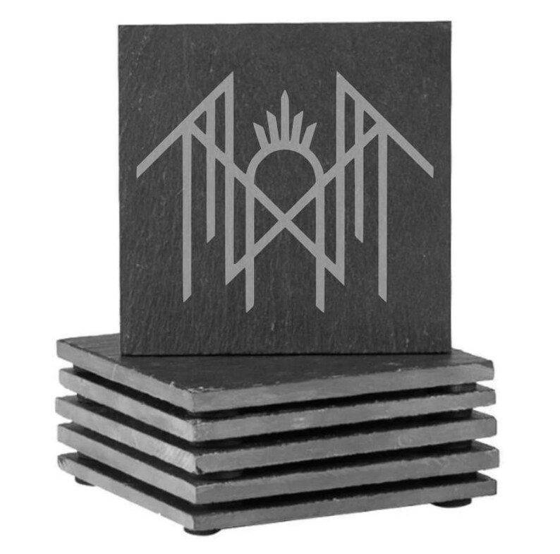 A stack of gray slate coasters with a stylized graphic design on them.