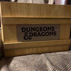 May include: A wooden box with a brown label that says "Dungeons & Dragons" in a black font.