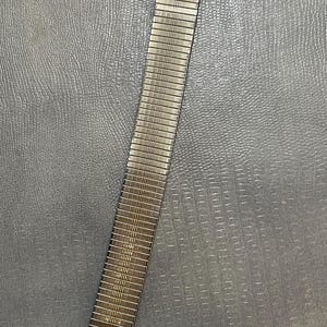 Puede incluir: Una pulsera de reloj de metal plateado con un acabado texturizado.