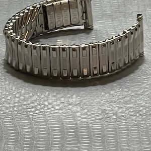 May include: A silver metal watch band with a clasp that says "Orologio" on it.