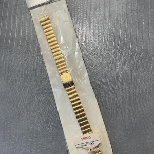 May include: A gold-colored watch band in a clear plastic package. The band is labeled "SEIKO S-G5159G".