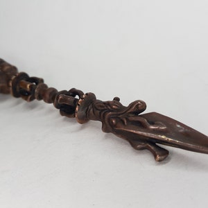 May include: An ornate bronze dagger with a detailed handle and a pointed blade. The handle features intricate carvings and a decorative head. The dagger is likely a ceremonial or decorative item.