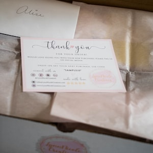 May include: A rectangular thank you card with a light pink border, featuring the text thank you for your order, social media icons, a discount code SAMPLE10, and the brand name LynnNicole Creations, placed inside a cardboard box with tissue paper.