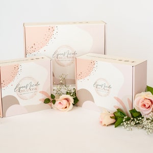 May include: Three pink and white gift boxes with a gold and white abstract design. The boxes have the text "Lynn Nicole Creations" on them. The boxes are surrounded by pink roses and white baby's breath.