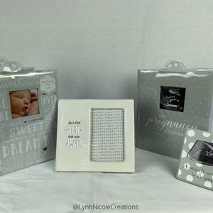 May include: Three gray photo albums with white polka dots and silver accents. The albums are for baby memories, pregnancy, and ultrasound photos. The text on the albums reads "You are my sunshine", "My Pregnancy Journal", and "A miracle waiting to be seen".