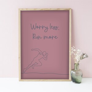 Puede incluir: Una cita motivacional, "Worry less, Run more", impresa en un fondo rosa en un p&oacute;ster enmarcado. Un simple dibujo de l&iacute;nea de un corredor est&aacute; debajo del texto.