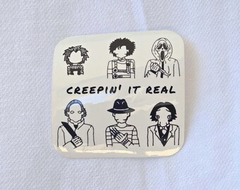 Peut inclure: Un autocollant carré blanc cassé avec des illustrations au trait noir de six personnages de films d'horreur. Le texte "CREEPIN' IT REAL" est imprimé en noir. L'autocollant est sur une surface blanche texturée.