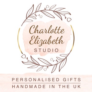 Op de afbeelding: Een gouden cirkel met een roze aquarel achtergrond en een krans van bloemen. De tekst "Charlotte Elizabeth STUDIO" is geschreven in bruin cursief schrift.