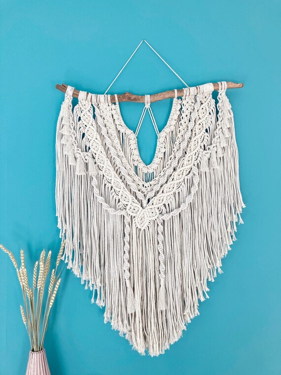 A named, handcrafted macramé wall piece — 'Flora' suggests a sculptural, botanical-inspired fiber art work with genuine artisan character at a premium price point that signals real craft investment.