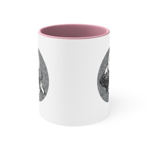 May include: White ceramic mug with a pink rim. The mug features a black and white illustration of a skull with a crown on top.