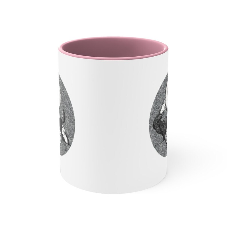 May include: White ceramic mug with a pink rim. The mug features a black and white illustration of a skull with a crown on top.