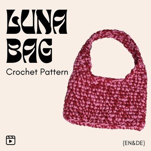 Könnte beinhalten: Handgefertigte Häkeltasche in Rot- und Rosatönen mit rundem Henkel. Der Text "LUNA BAG Crochet Pattern" ist in schwarzer, stilisierter Schrift dargestellt. Der Hintergrund ist hellbeige.