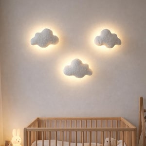 Könnte beinhalten: Ein Kinderzimmer mit einem Holzbett, weicher Bettwäsche und einem Teddybär. Drei wolkenförmige Wandleuchten beleuchten den Raum. Eine Hasenlampe steht auf einem Nachttisch. Der Raum hat eine neutrale Farbpalette mit einem Korb und einem Teppich.