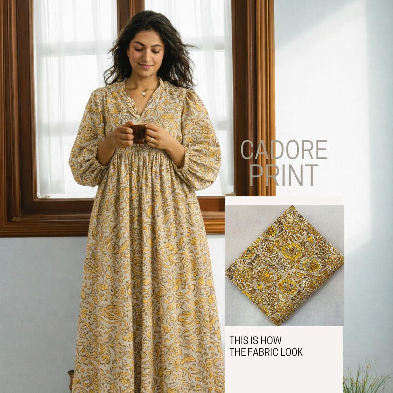 May include: A long-sleeved dress featuring the Cadore print, which consists of a beige background with a repeating yellow and brown floral pattern. The dress has a V-neckline and a gathered waist. A swatch of the fabric is shown separately.