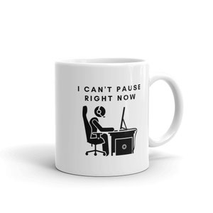 May include: White ceramic mug featuring a black graphic of a person with a headset at a computer desk. The text "I CAN'T PAUSE RIGHT NOW" is printed above the graphic, ideal for gamers.