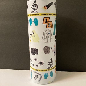 May include: A white stainless steel tumbler with a crime scene theme. The tumbler is covered in various crime scene related images, including a microscope, a flashlight, a pair of gloves, a crime scene tape, a camera, a fingerprint, a DNA strand, bullet holes, and a lab coat. The text "DO NOT CROSS CRIME SCENE" is printed on the tumbler.