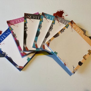 May include: Six colorful notepad sets with the word "NOTES" printed on the front. Each notepad has a different design featuring a variety of illustrations, including a microscope, a fingerprint, and a pair of handcuffs.